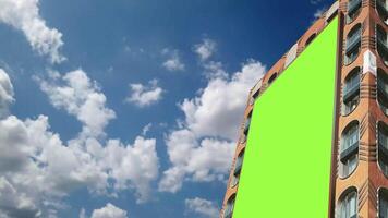 Chroma Key Green screen vertical billboard on modern building for advertising with bright sky and moving clouds background video