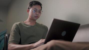 Focused concentration a young man with glasses gazes intently at his laptop, engrossed in work, reflecting the dedication and focus required for modern-day success. video