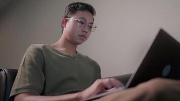 A young man sitting intently working in a relaxed atmosphere with his laptop on his lap and staring at the computer screen. video