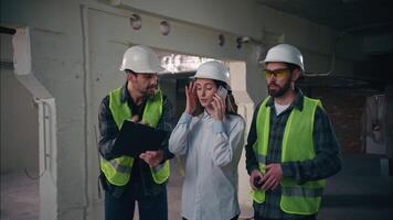 Three Caucasian workers construction builders problem chaos accident developer inspector team woman talk mobile phone men arguing talking walkie talkie trouble difficulty engineers discuss build plan video