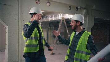 Two happy Caucasian men greeting friends buddies males guys workers in uniform helmets business construction teamwork engineers architects meeting shaking hands building cooperation colleagues gesture video