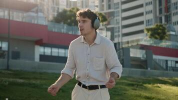 Caucasian man dancing listening music headphones earphones technology enjoyment weekend relax sound moving male guy outdoor energetic songs sing cheerful businessman business city wireless mp3 student video