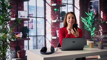 Woman freelancer taking online course to develop new skills from home office, attend online call and watching lecture on smartphone. Lady participates at virtual training class. Camera B. video