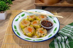 A traditional Chinese food. A plate of dim sum on a white tin plate with chili oil and chopsticks. photo