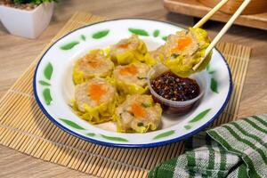 A plate of dim sum on a tin plate and hold with chopsticks. A traditional Chinese food. photo