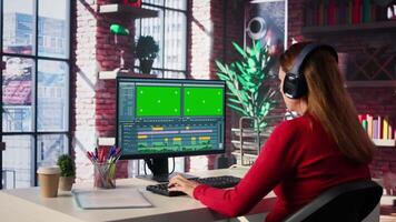 Female videographer works on editing a movie montage with chroma key, multitasking with her computer setup at home. Woman editor starting the cinematic creative process, industry. Camera B. video