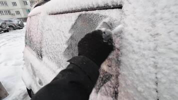 A person is cleaning the window of a car with snow video