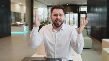 Angry businessman raising hands in indignant expression, asking reason of failure in office lobby video