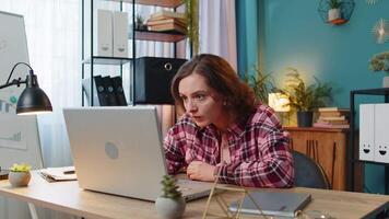 Displeased sad woman using working on laptop loss game fail computer virus at home office table video