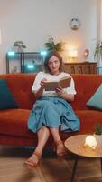 Irritated young woman reading book cover ears with pillows annoyed by loud noise sitting on sofa video