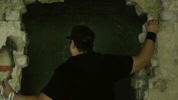 Muscular male breaking forcefully through heavy metal chains, straining against constraints in shadowy green lit chamber with crumbling wall, symbolizing personal liberation and inner strength video