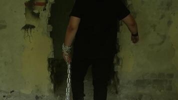 Hooded figure straining against chained wrists, breaking through decaying brick wall, symbolizing raw struggle for personal liberation and overwhelming inner strength video