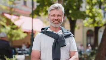 Portrait of happy bearded mature man smiling friendly, glad expression looking at camera relaxation video