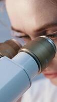 Scientist adjusting microscope, conducting research in a modern laboratory. The lab is equipped with advanced technology, reflecting the cutting edge nature of her work video