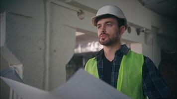 Caucasian builder man handyman guy foreman holding blueprint architect male inspecting building electrician employee work in factory construction engineer supervising manufacturing architecture draft video
