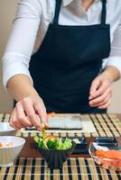 Chef picking up sliced avocado to make sushi photo