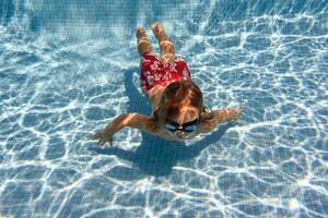 Boy swimming near bottom in pool photo