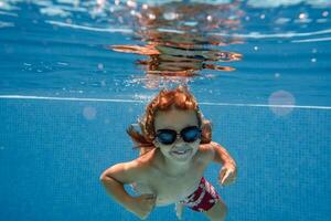 Excited boy in goggles swimming in pool photo