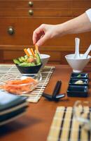 Chef hand picking up a crab stick to make sushi photo