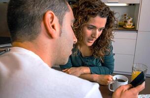 Couple having breakfast and looking mobile photo