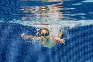 Active boy swimming in clear pool water photo