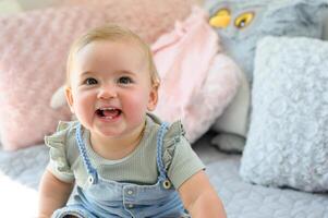 Cheerful little toddler sitting on soft bed looking at camera photo