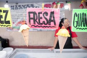 Nut and strawberry flavor signs in an ice cream street market stall with an Hispanic woman in the background photo