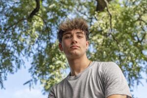 Low angle of a young man, serious, looking at the camera in a pu photo