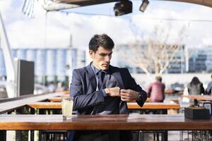 A pensive man looking for his smartphone in his pocket to check something photo