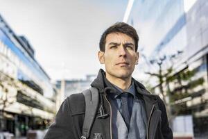 Low-angle view of an attractive businessman with his backpack on looking away while walking from his office photo
