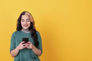 Portrait of an attractive woman using smart phone over yellow background. Copy space photo