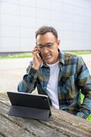 Smiling man talking on phone and using laptop photo