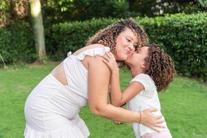 A girl kisses her mother on the cheek in the open air photo