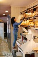 Sales clerk taking bread from the shelf photo