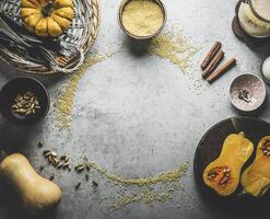 Pumpkin cooking background frame with millet , cinnamon sticks, cardamom and kitchen utensils. Top view photo