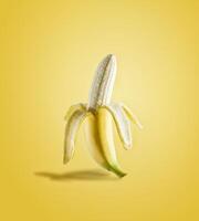 Half peeled banana in sunlight on yellow background. Delicious tropical fruit. Front view. photo