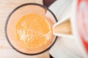 Close up of the bubbles of a fresh carrot juice being filled from a traditional squeezer. photo