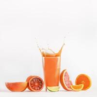 Splashing of citrus juice in glass with blood orange, grapefruit and lime at white background. Refreshing healthy drink with vitamins. Liquid in motion. Front view. photo