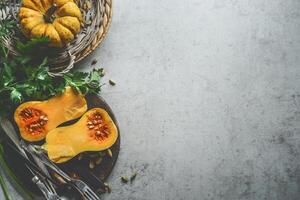 Healthy seasonal food background with pumpkins, fresh herbs and cutlery on rustic background, top view. Border photo