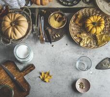 Autumn food background with pumpkins, cutting board and knife, various spices and kitchen utensils. Top view photo
