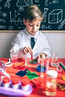 Kid playing to be chemist with colorful liquids photo