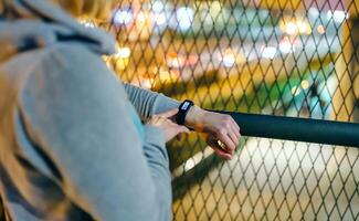 Unrecognizable female hands touching digital wrist band to check step counter after walking at night photo