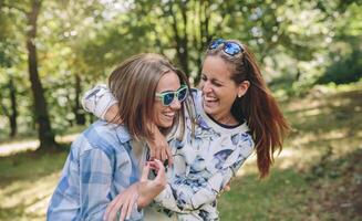 Happy women embracing and laughing over nature background photo