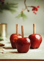 Red apples with cinnamon sticks on kitchen table with sugar at wall background with fir green. Sugar glazed apples. Delicious Christmas sweets. Front view. photo