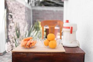 A table is ready to make orange and carrot juice with a traditional squeezer in the garden photo