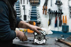 Professional mechanic assembling vehicle engine details at workbench photo