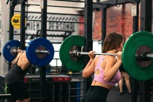man and woman preparing to do squats in a gym photo