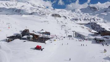 Aerial view of Cervino Ski Paradise resort with skiers in motion, snowy slopes, modern facilities, and the Matterhorn mountain in the background. video