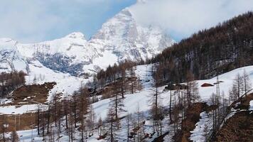 Aerial view of Cervino Ski Paradise resort and Cervino town with the Matterhorn mountain, snow covered slopes, and trees in a winter setting. video