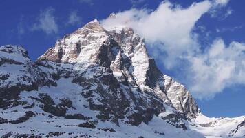 Aerial view of the Matterhorn mountain from the Italian side, showing its pyramid like peak, drifting clouds, and snow covered slopes in a slow pan. video